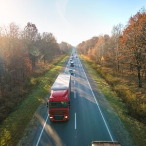 Aerial view of semi-truck with cargo trailer driving on highway hauling goods in evening. Delivery